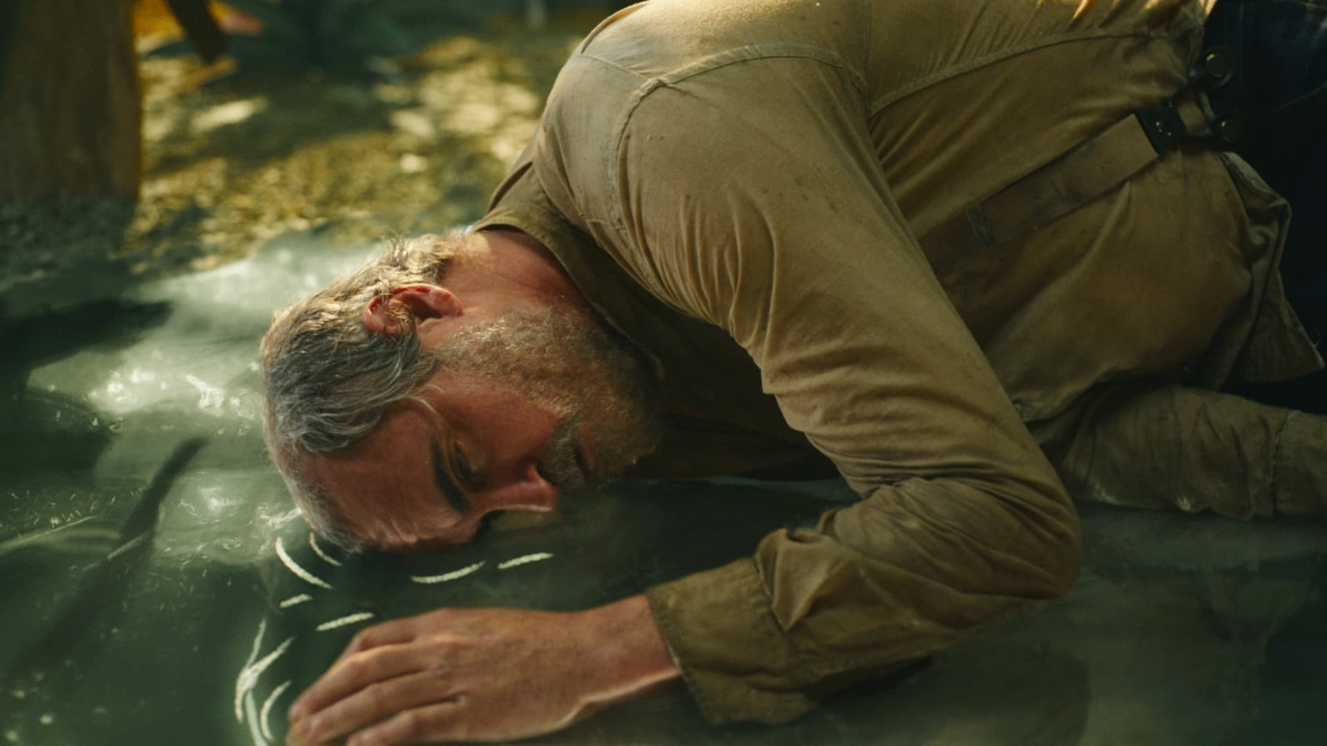 Joaquin Phoenix cradled against a puddle.