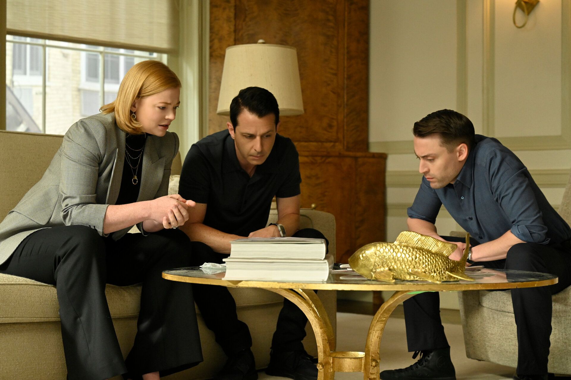 Sarach Snook, Jeremy Strong, and Kieran Culkin peer over a coffee table in 'Succession' season 4, episode 4.
